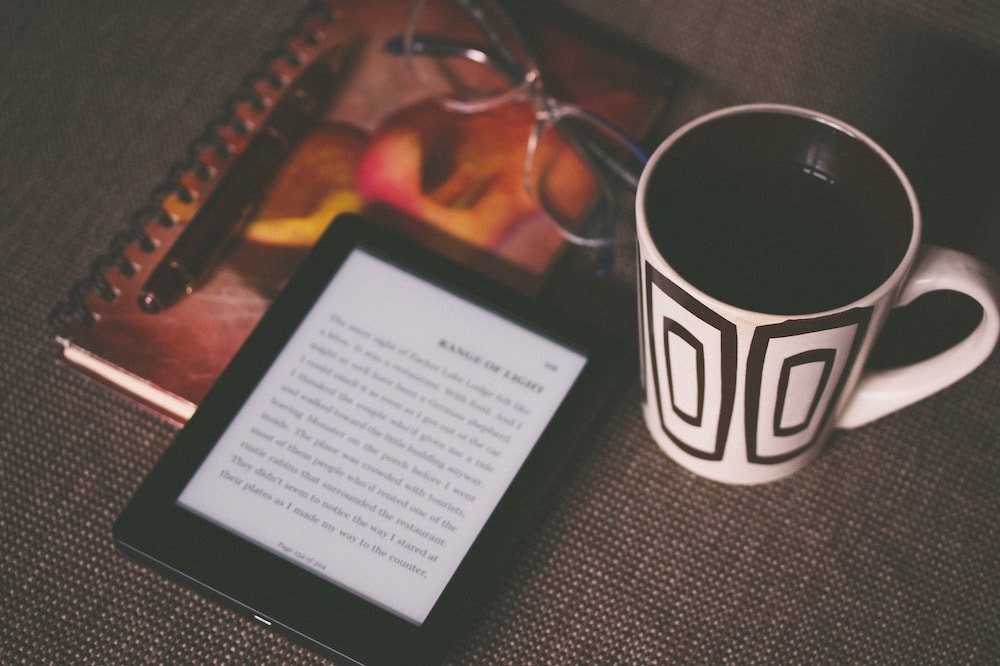 A Kindle, mug, and notepad.